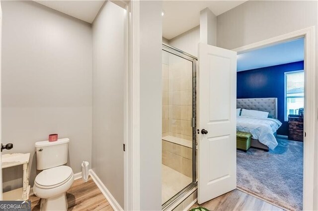 ensuite bathroom with ensuite bathroom, baseboards, toilet, wood finished floors, and a stall shower