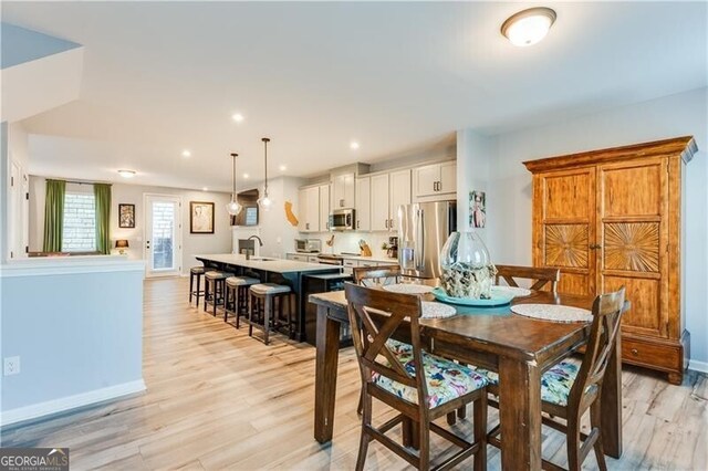 dining area featuring baseboards, light wood finished floors, and recessed lighting