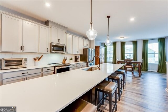 kitchen featuring light countertops, stainless steel appliances, a breakfast bar, a toaster, and a sink