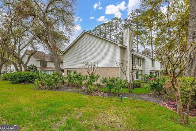 809 Mallery St Unit A, Saint Simons, GA 31522 - view of property exterior featuring a lawn, a chimney, and brick siding