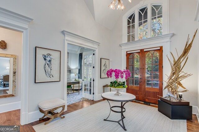 foyer featuring a wealth of natural light, high vaulted ceiling, baseboards, and wood finished floors