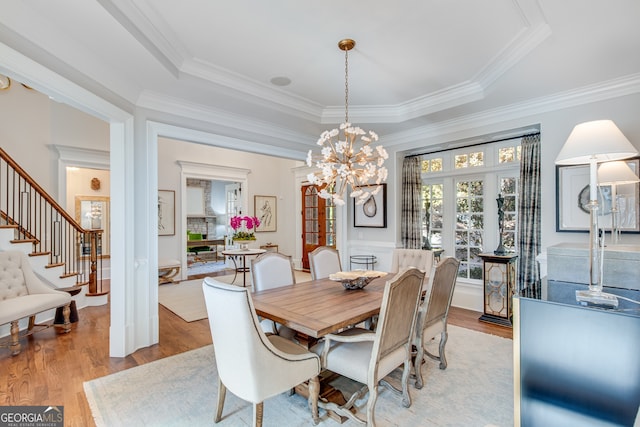 dining area featuring wood finished floors, a notable chandelier, and a raised ceiling