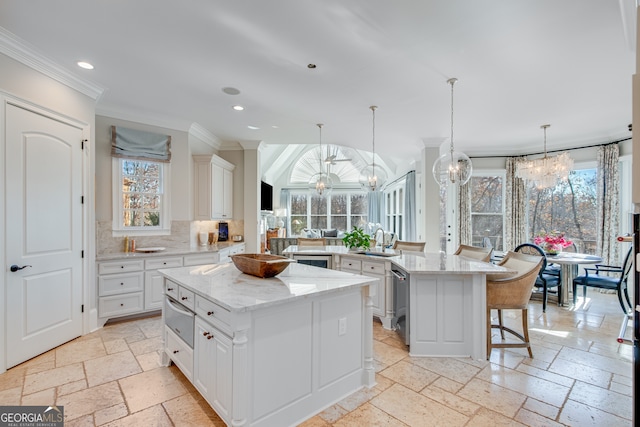 kitchen featuring a sink, a chandelier, a spacious island, and stone tile flooring