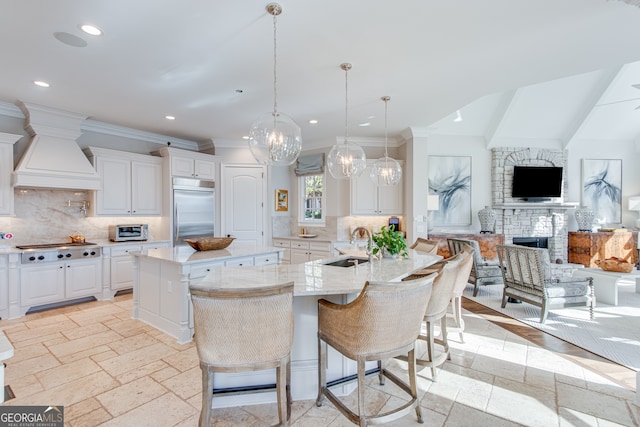 kitchen featuring stainless steel appliances, a sink, custom range hood, a center island, and stone tile floors