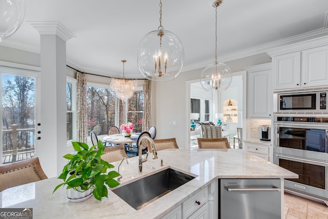 kitchen with ornamental molding, a sink, a notable chandelier, and appliances with stainless steel finishes