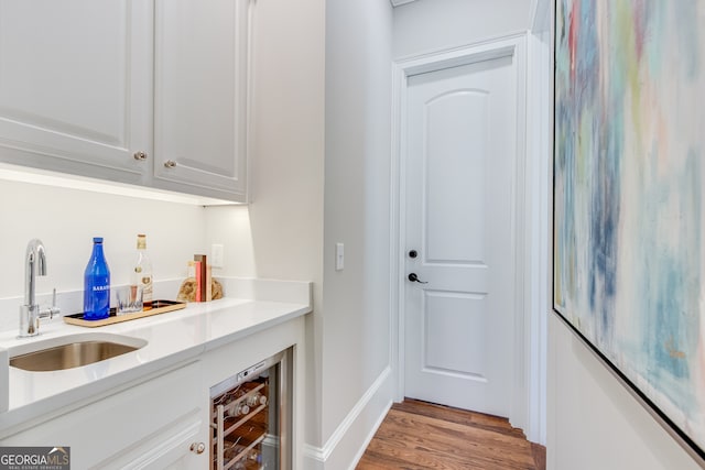 bar featuring beverage cooler, wood finished floors, a sink, and indoor bar
