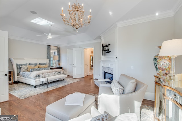 bedroom with wood finished floors, a glass covered fireplace, and crown molding