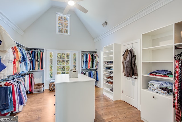 spacious closet featuring high vaulted ceiling, light wood-style flooring, visible vents, and a ceiling fan