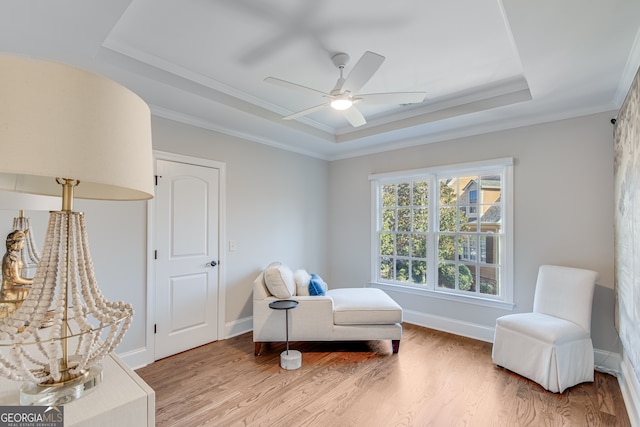 sitting room featuring baseboards, light wood-type flooring, ceiling fan, and a raised ceiling