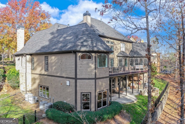 back of property with a chimney, fence, roof with shingles, and a patio