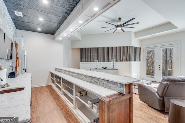 kitchen featuring light wood-type flooring, light stone counters, ceiling fan, and visible vents