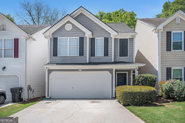 traditional-style home with concrete driveway, roof with shingles, and a garage