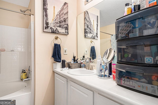 bathroom with a textured ceiling, bathing tub / shower combination, and vanity