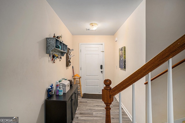 entryway featuring visible vents, baseboards, light wood-style flooring, and stairs