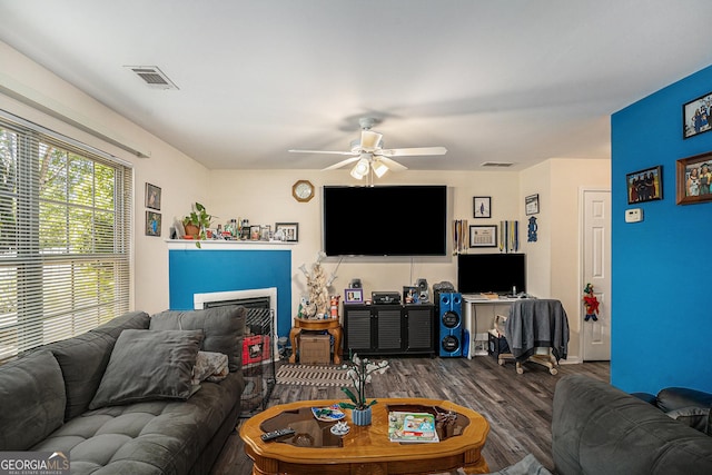 living area with a fireplace, a ceiling fan, wood finished floors, and visible vents