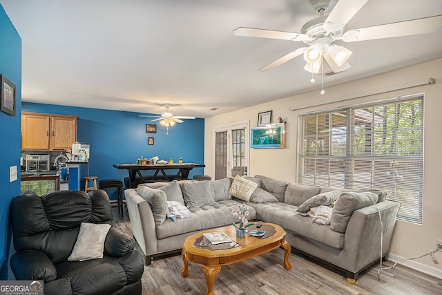 living room featuring light wood-style floors, baseboards, plenty of natural light, and a ceiling fan