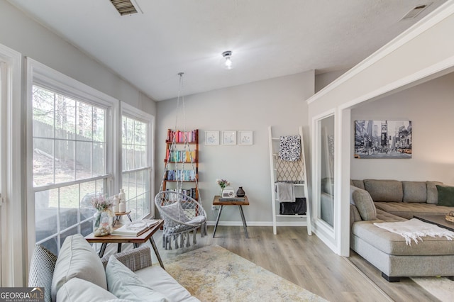 living area with wood finished floors, visible vents, and baseboards