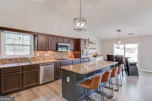kitchen with decorative backsplash, appliances with stainless steel finishes, a sink, and light wood-type flooring