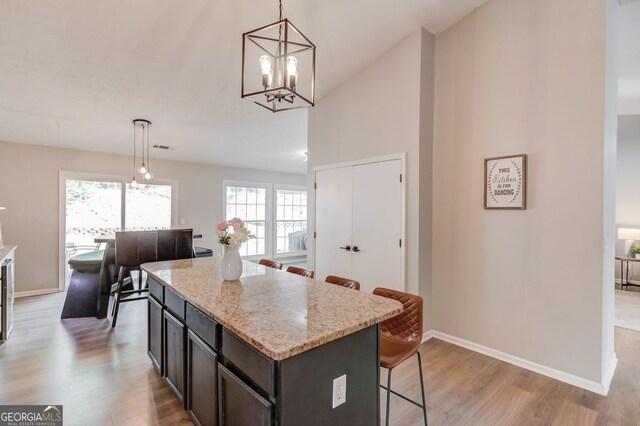 kitchen with a kitchen bar, light wood-type flooring, hanging light fixtures, and baseboards