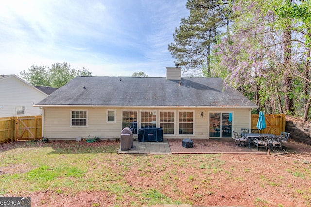 back of house featuring a chimney, a gate, fence, a yard, and a patio area