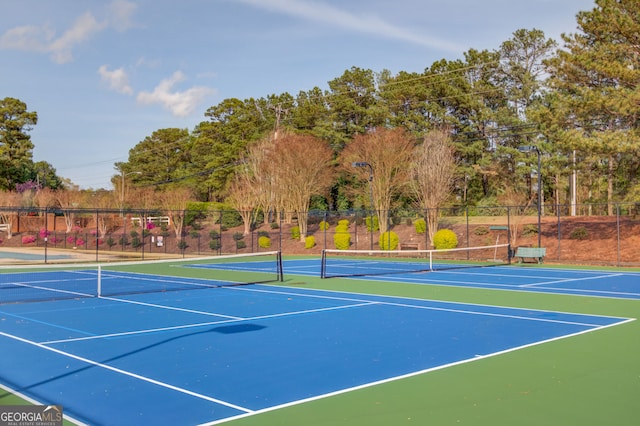 view of tennis court featuring community basketball court and fence