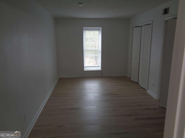 unfurnished bedroom with light wood finished floors, baseboards, and visible vents