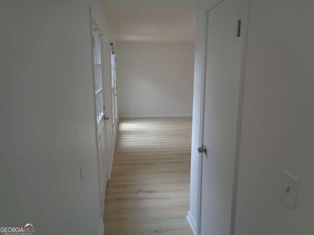 hall featuring baseboards and light wood-type flooring