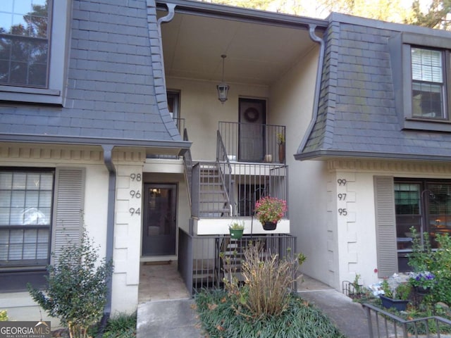 entrance to property featuring stucco siding and mansard roof
