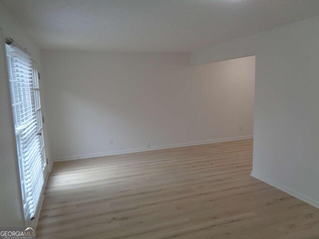 spare room with baseboards and light wood-style floors