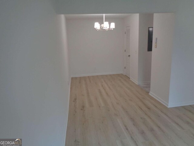 unfurnished dining area with baseboards, wood finished floors, and a chandelier