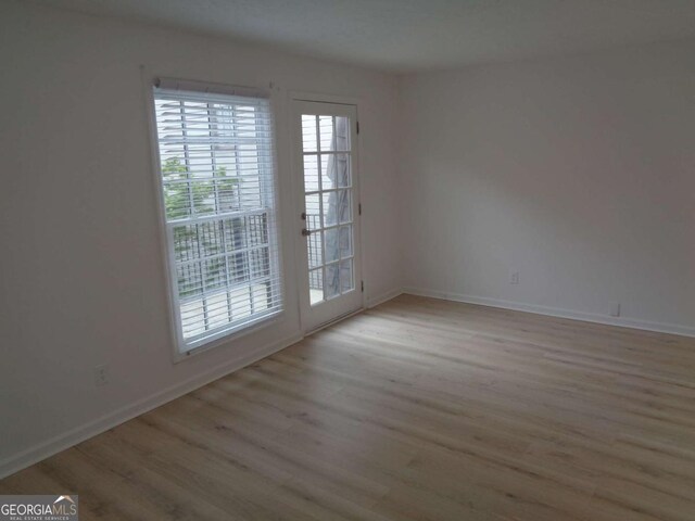 spare room with baseboards and wood finished floors