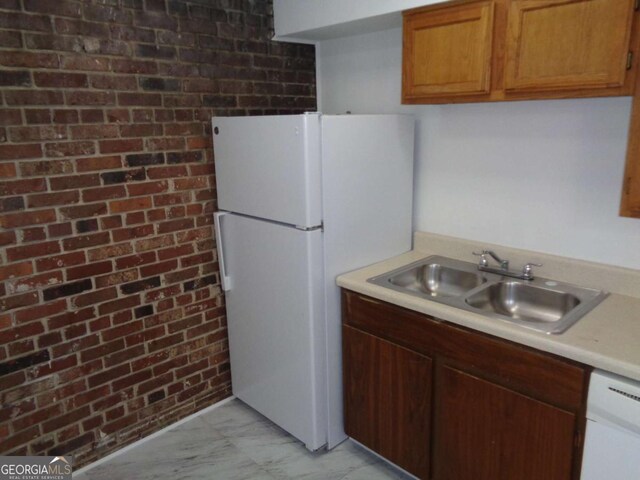 kitchen with light countertops, white appliances, marble finish floor, a sink, and brick wall