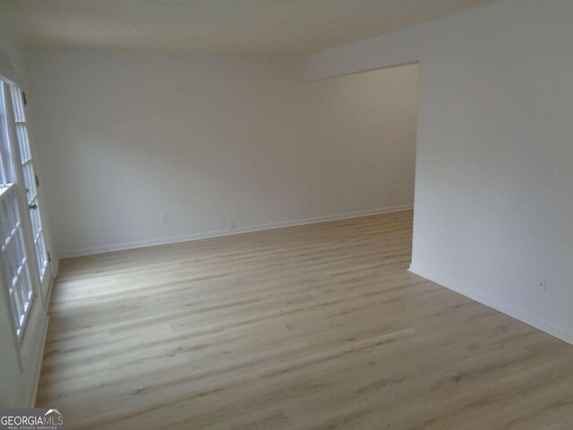 spare room featuring baseboards and light wood-style floors