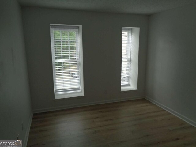 empty room with baseboards and wood finished floors