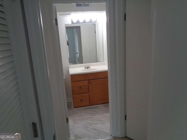 corridor featuring marble finish floor, visible vents, and a sink