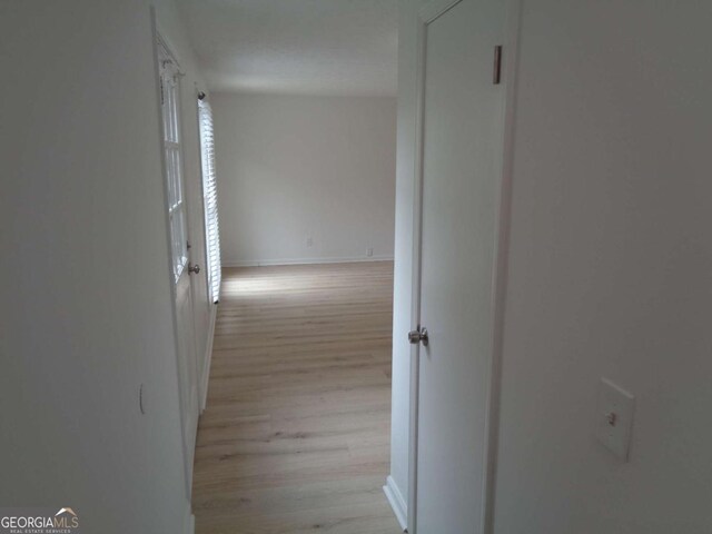 hall featuring baseboards and light wood-type flooring