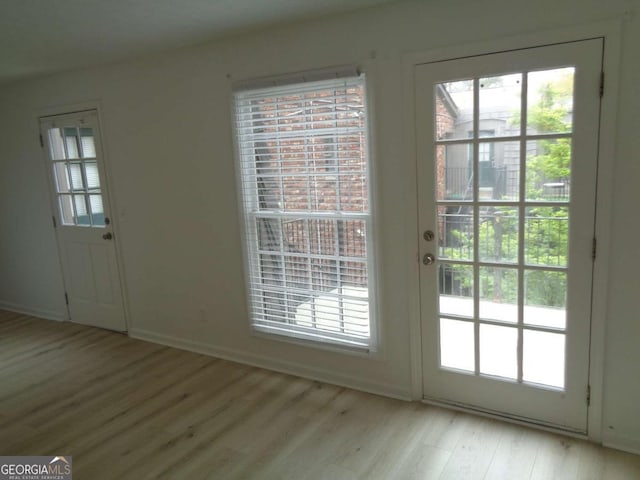doorway featuring baseboards and light wood-style floors