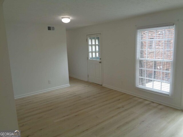 unfurnished room with baseboards, visible vents, and light wood-style floors