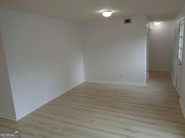 empty room featuring light wood-type flooring, baseboards, and visible vents