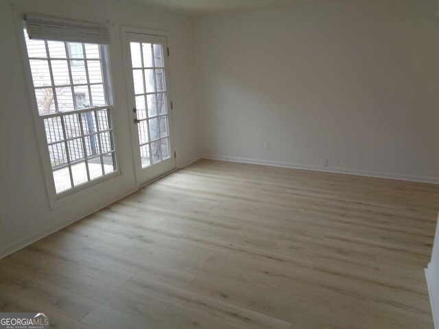 unfurnished room with baseboards and light wood-style flooring