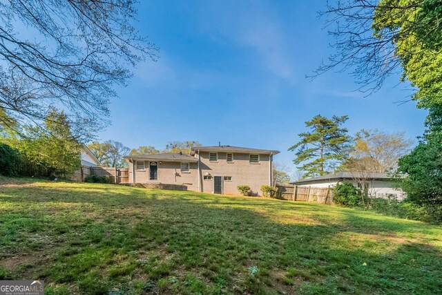 rear view of property with a lawn and fence