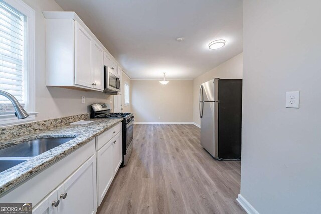 kitchen featuring white cabinets, a sink, appliances with stainless steel finishes, and light wood finished floors