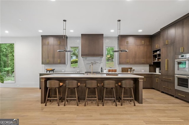 402 Chattahoochee St, Roswell, GA 30075 - kitchen with stainless steel double oven, a kitchen island with sink, light wood-style floors, light countertops, and recessed lighting
