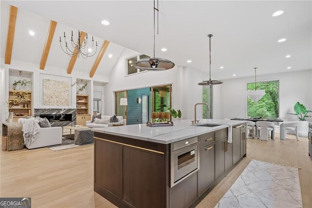 402 Chattahoochee St, Roswell, GA 30075 - kitchen with light wood finished floors, dark brown cabinetry, a center island with sink, decorative light fixtures, and recessed lighting