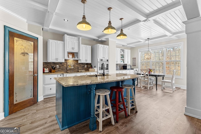 1452 Redwine Rd, Fayetteville, GA 30215 - kitchen with coffered ceiling, decorative backsplash, light stone counters, stainless steel oven, and white cabinetry