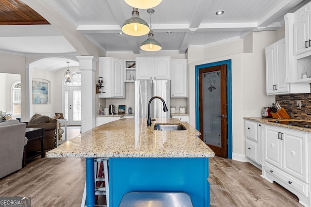 1452 Redwine Rd, Fayetteville, GA 30215 - kitchen featuring decorative columns, arched walkways, backsplash, light wood-style flooring, and white cabinetry