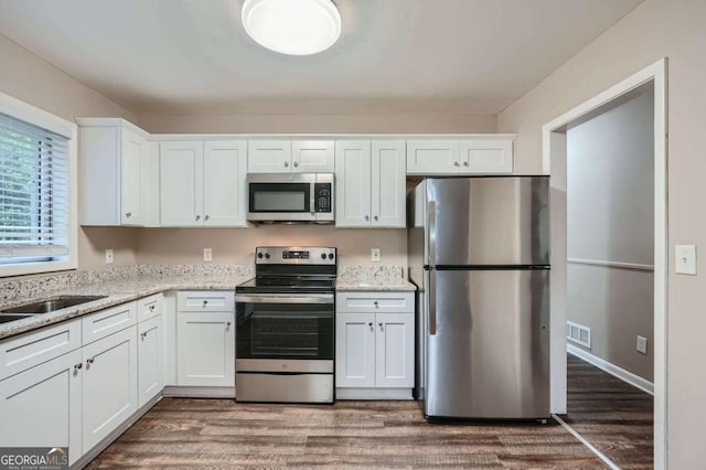 2184 Pemberton Rd SW, Atlanta, GA 30331 - kitchen featuring stainless steel appliances, white cabinetry, wood finished floors, and light stone counters