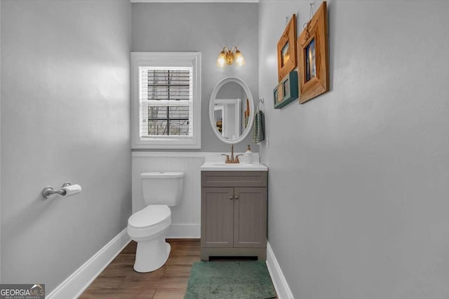 bathroom featuring toilet, vanity, baseboards, and wood finished floors