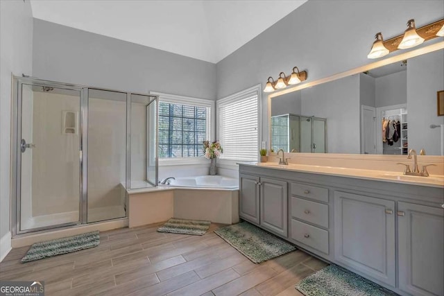 bathroom with wood finish floors, a sink, a bath, and a shower stall