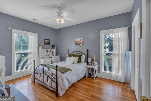 bedroom featuring visible vents, wood finished floors, multiple windows, and a ceiling fan